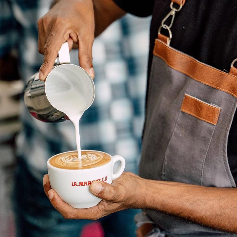 SkinnyTom's barista pouring specialty latte art on La Marzocco cup