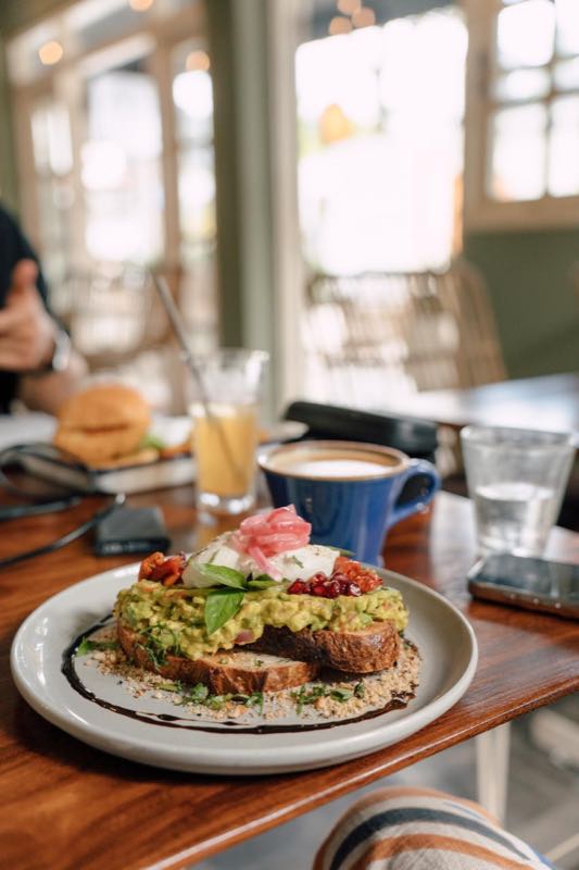 Smashed avocado toast on artisan sourdough with poached egg and pomegranate